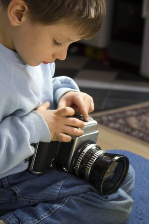 Young boy examining a vintage medium format cameraの写真素材