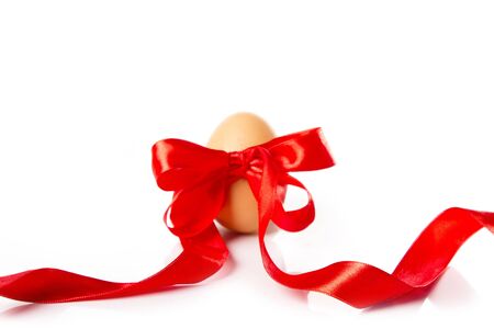 Yellow egg bounded in red ribbon. Isolated on whiteの写真素材