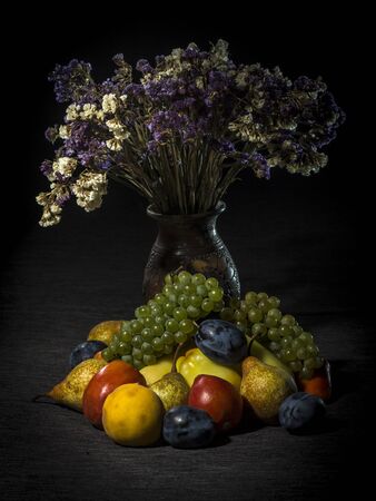 Organic fruits and vegetables on dark background with flowersの写真素材