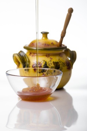 Honey pouring to glass mug on white backgroundの写真素材