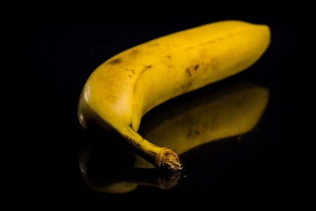 One fresh, yellow banana on black background with reflectionの写真素材