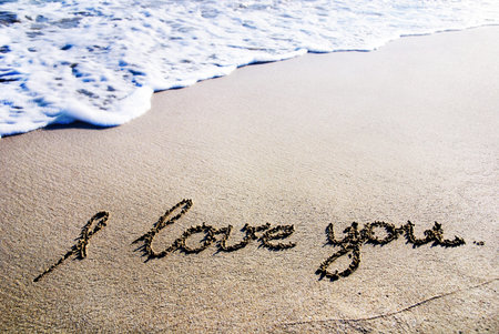 words "I love you" outline on the wet sand with the wave brillianceの写真素材