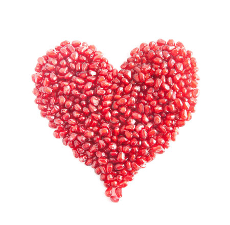 ripe pomegranate seeds in form of heart isolated on white background - love conceptの写真素材