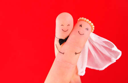 just married couple, newlyweds painted at fingers against red background, good use for wedding invitation cardの写真素材