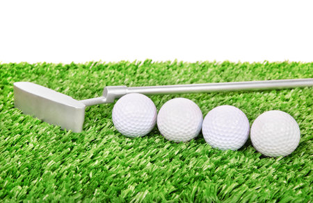 Golf balls and club on green field grass