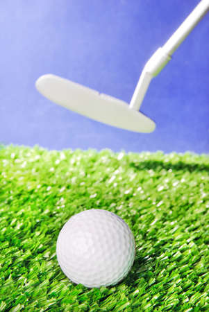 Golf ball and club on green field grass against blue sky - vertical imageの写真素材
