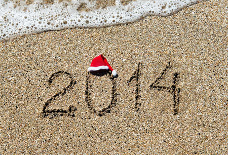 happy new year 2014 with christmas hat on sandy beach with wave - holiday conceptの写真素材