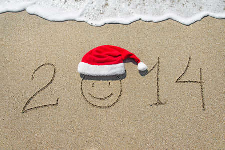 happy new year 2014 with smiley face in christmas hat on sandy beach - holiday conceptの写真素材