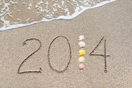 inscription 2014 on sea sand beach with seashellsの写真素材