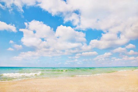 Beautiful panorama of sandy sea beach with waves and blue cloudy skyの写真素材