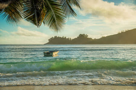 Tropical beach Baie Lazare with boat at sunset, Mahe island, Seychelles - vacation backgroundの写真素材