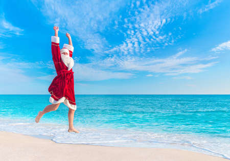 Santa Claus (Father Christmas) jump at sea sandy beach in the sky - New Year's vacation in hot countries conceptの写真素材