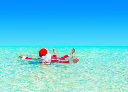 Santa Claus relax swimming in ocean turquoise transparent water. Merry Christmas and Happy New Year travel destinations concept.の写真素材