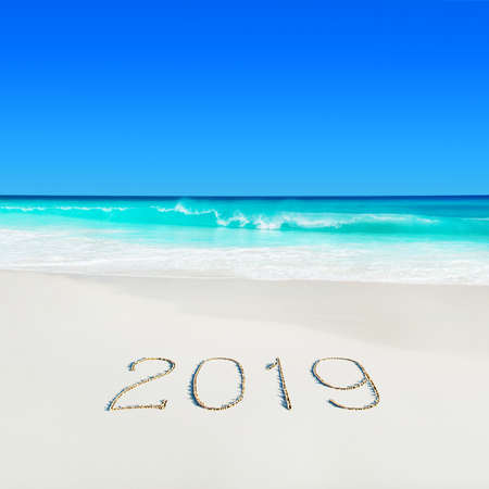 Turquoise ocean water at tropical white sandy beach and season 2019 handwritten caption on sand.の写真素材