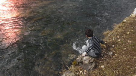 Young boy enjoying the picturesque view of the river.