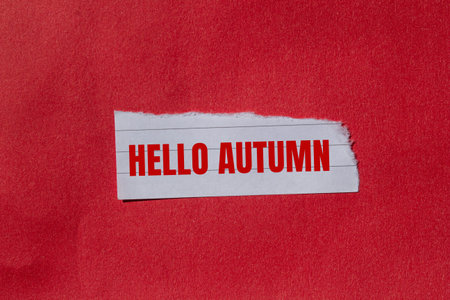 Hello autumn message written on torn torn paper piece with red background. Conceptual hello autumn...