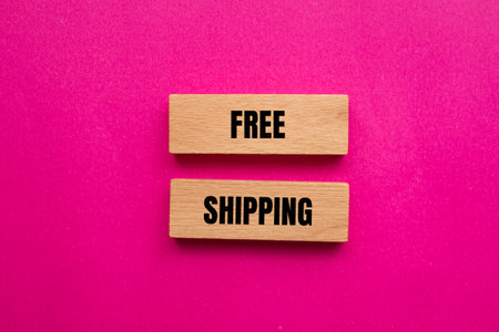 Free shipping message written on wooden blocks with pink background. Conceptual free shipping symbol. Copy space.の写真素材