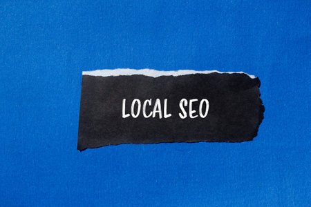 Local seo message written on torn torn black paper piece with blue background. Conceptual local seo symbol. Copy space.の写真素材