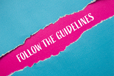 Follow the guidelines message written on ripped blue paper with pink background. Conceptual follow the guidelines symbol. Copy space.の写真素材