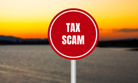 Tax scam message written on red sign on blurry lake background at sunset. Conceptual tax scam symbol. Copy space.の写真素材