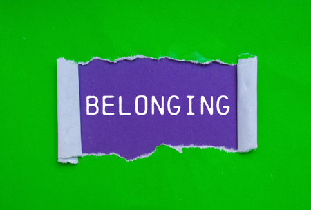 Belonging message written on ripped torn green paper on purple background. Conceptual belonging symbol. Copy space.の写真素材