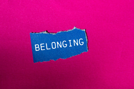 Belonging message written on ripped blue torn paper piece on pink background. Conceptual belonging symbol. Copy space.の写真素材
