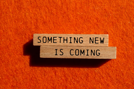 Something new is coming message written on wooden blocks on orange felt background. Conceptual something new is coming symbol. Copy space.の写真素材