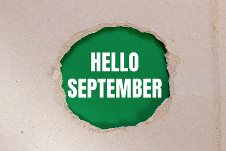 Hello september message written on ripped torn paper with green background. Conceptual hello september symbol. Copy space.の写真素材