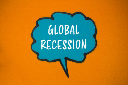 Global recession message written on blue paper speech bubble with orange background. Conceptual global recession symbol. Copy space.の写真素材