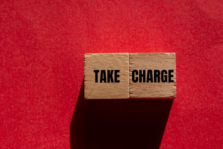 Take charge message wooden cubes on red background. Conceptual take charge symbol. Copy space.の写真素材