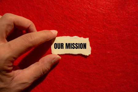 Our mission message written on torn torn paper piece with red background. Conceptual our mission...