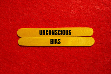 Unconscious bias message written on yellow wooden sticks with red background. Conceptual unconscious...