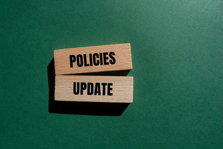 Policies update message written on wooden blocks with green background. Conceptual policies update...