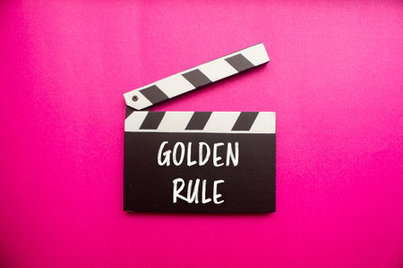 Golden rule message written on clapperboard with pink background. Conceptual golden rule symbol....