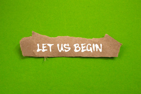 Let us begin message written on torn brown paper piece on green background. Conceptual let us begin symbol. Copy space.の写真素材