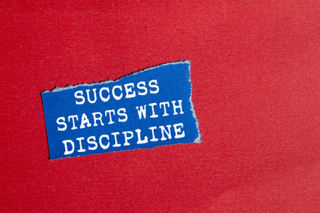 Success starts with discipline message written on ripped torn blue paper piece on red background....