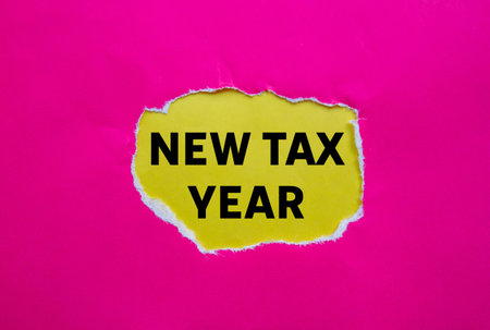 New tax year message written on ripped torn pink paper on yellow background. Conceptual new tax year symbol. Copy space.の写真素材