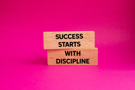 Success starts with discipline message written on wooden blocks on pink background. Conceptual success starts with discipline symbol. Copy space.の写真素材