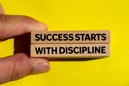 Success starts with discipline message written on wooden blocks on yellow background. Conceptual success starts with discipline symbol. Copy space.の写真素材