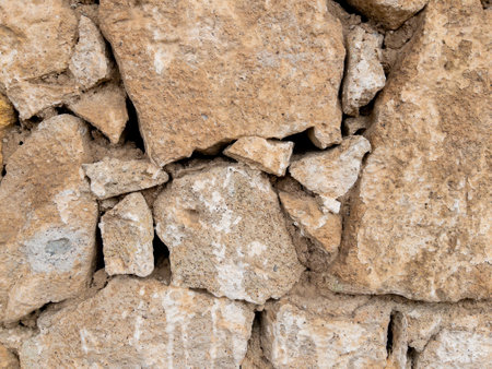 Weathered stone wall texture with cracked cement detailsの写真素材