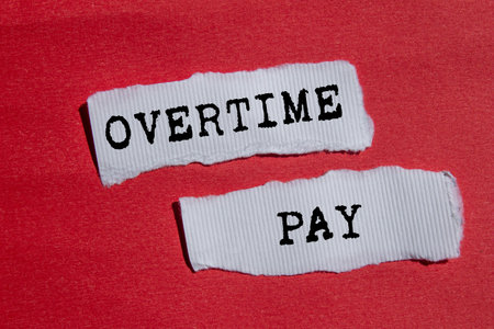 Overtime pay message written on torn torn white paper pieces on red background. Conceptual overtime pay symbol. Copy space.の写真素材