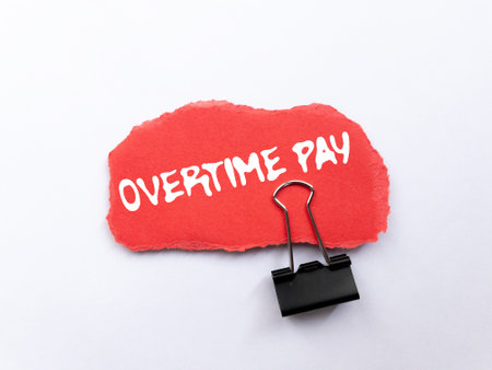 Overtime pay message written on ripped torn red paper piece on white background. Conceptual overtime pay symbol. Copy space.の写真素材