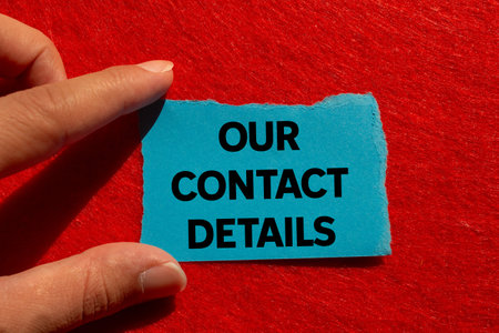 Our contact details message written on ripped torn blue paper on red background. Conceptual our contact details symbol. Copy space.の写真素材