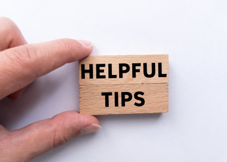 Helpful tips message written on wooden blocks on white background. Conceptual helpful tips symbol. Copy space.の写真素材