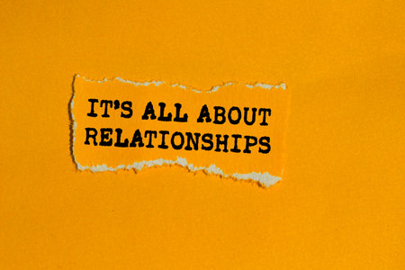 It's all about relationships message written on ripped torn orange paper piece on orange background. Conceptual it's all about relationships symbol. Copy space.の写真素材