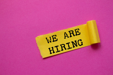 We are hiring message written on torn torn yellow paper piece on pink background. Conceptual we are hiring symbol. Copy space.の写真素材