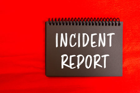 Incident report message written on black notebook page on red background. Conceptual incident report symbol. Copy space.の写真素材