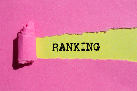 Ranking message written on ripped torn pink paper on yellow background. Conceptual ranking symbol. Copy space.の写真素材