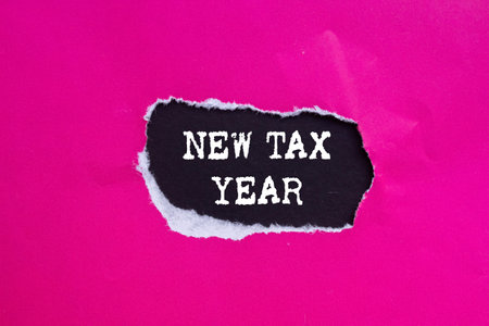New tax year message written on ripped torn pink paper on black background. Conceptual new tax year symbol. Copy space.の写真素材