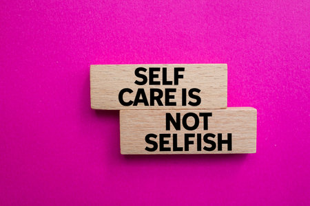 Self care is not selfish message written on wooden blocks on pink background. Conceptual self care is not selfish symbol. Copy space.の写真素材